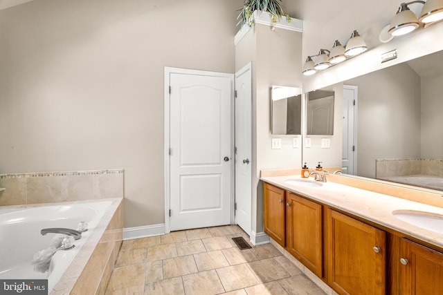 full bathroom featuring double vanity, baseboards, a sink, and a garden tub
