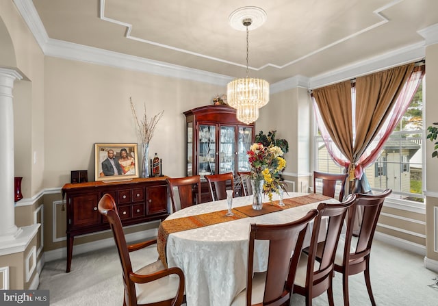 dining room featuring light colored carpet, crown molding, a notable chandelier, and ornate columns
