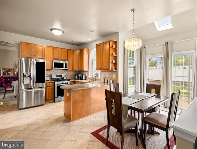 kitchen featuring a sink, open shelves, a peninsula, a chandelier, and stainless steel appliances