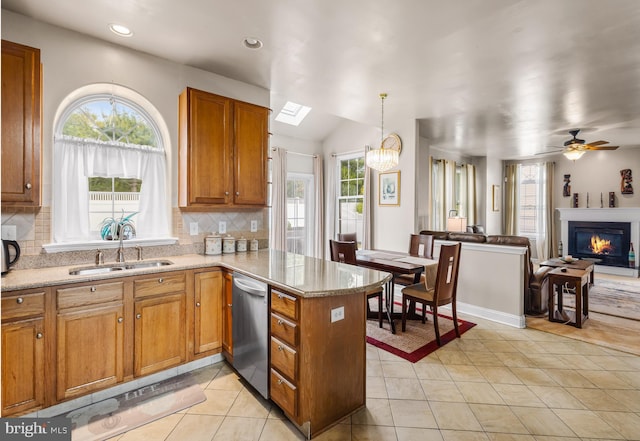 kitchen featuring a peninsula, a sink, brown cabinetry, stainless steel dishwasher, and tasteful backsplash
