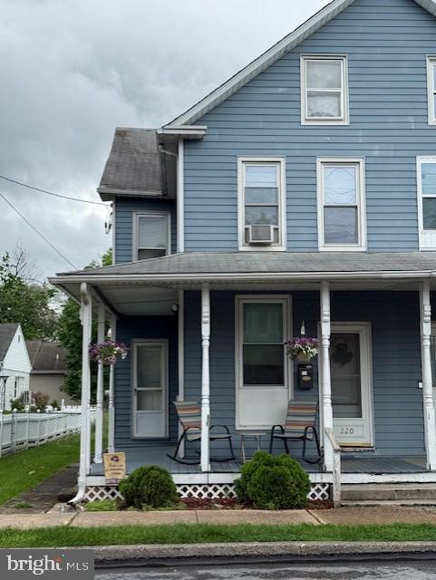 view of front of home featuring cooling unit, covered porch, and fence