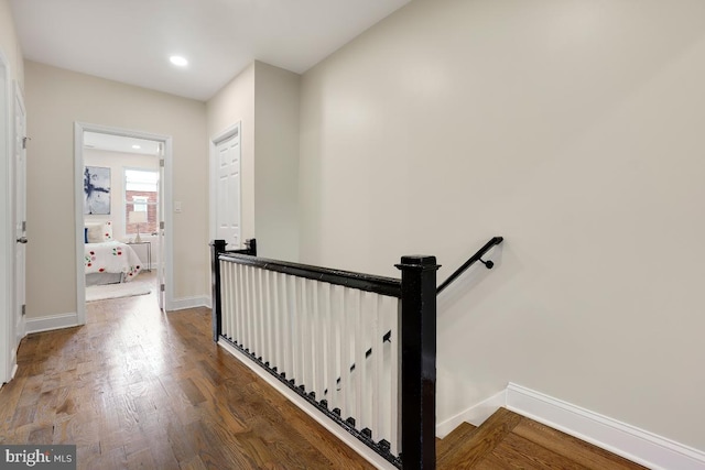 hallway with baseboards, an upstairs landing, recessed lighting, and wood finished floors