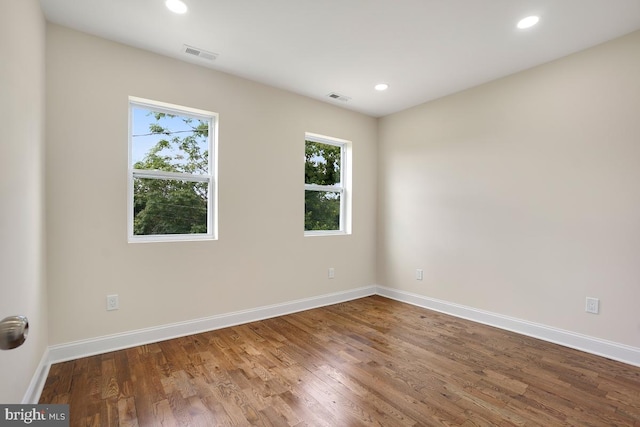 empty room featuring baseboards, visible vents, and wood finished floors