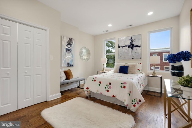 bedroom featuring a closet, wood finished floors, visible vents, recessed lighting, and baseboards