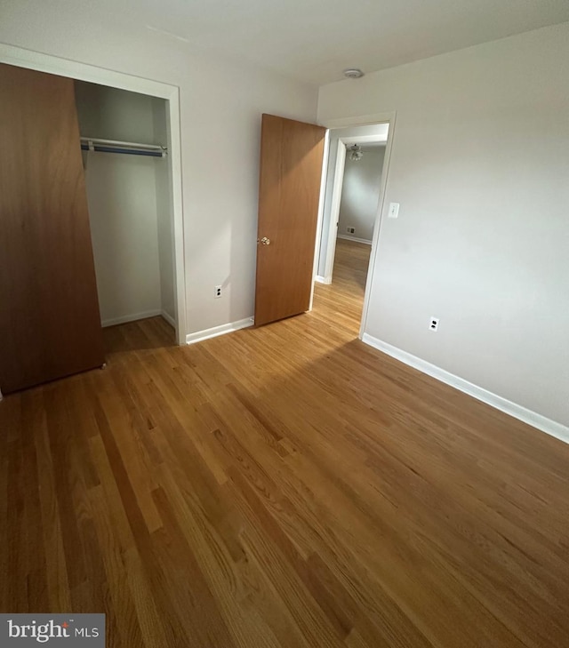 unfurnished bedroom featuring baseboards, a closet, and wood finished floors