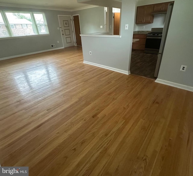 unfurnished living room featuring crown molding, light wood-style flooring, and baseboards