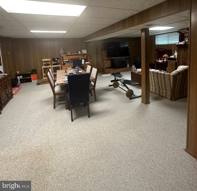 dining room with wooden walls, carpet flooring, and a drop ceiling