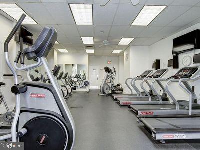 gym featuring a drop ceiling and ceiling fan