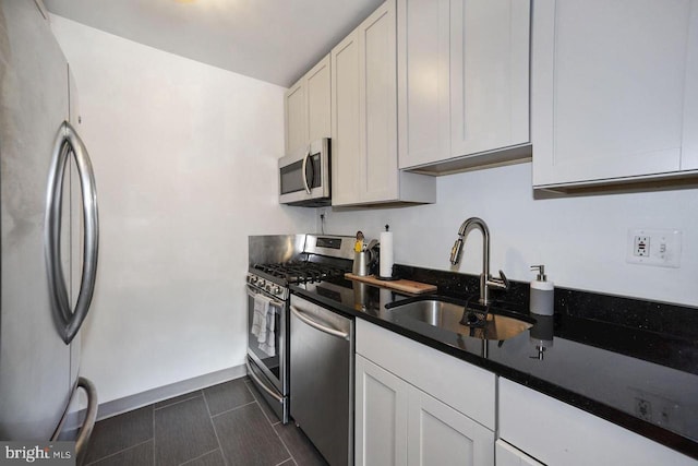 kitchen with white cabinetry, stainless steel appliances, baseboards, and a sink