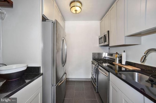 kitchen featuring a sink, baseboards, white cabinets, and appliances with stainless steel finishes