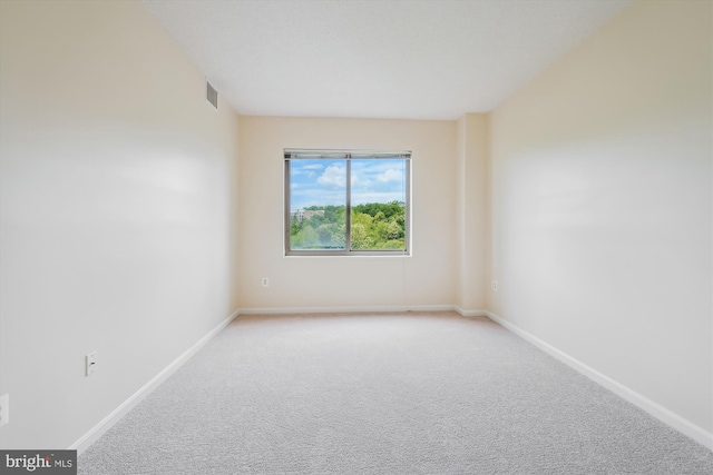 carpeted empty room featuring baseboards and visible vents