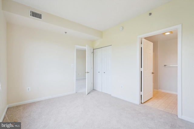 unfurnished bedroom featuring carpet flooring, baseboards, a closet, and visible vents