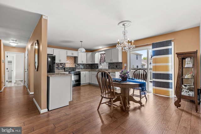 dining space with a chandelier, dark wood finished floors, baseboards, and beverage cooler