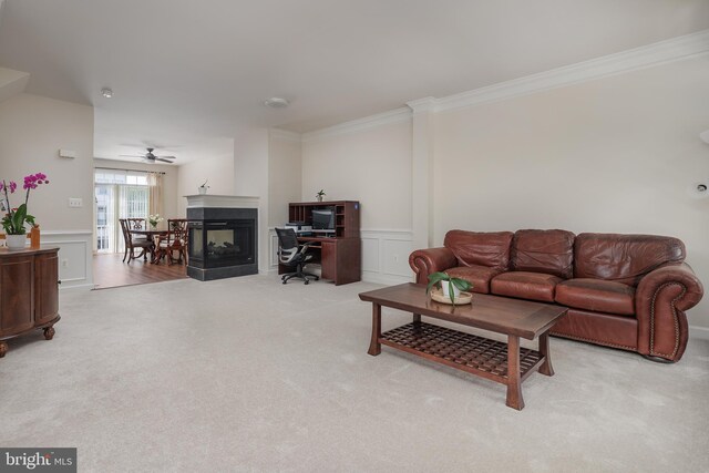 living area featuring carpet floors, crown molding, a decorative wall, wainscoting, and ceiling fan