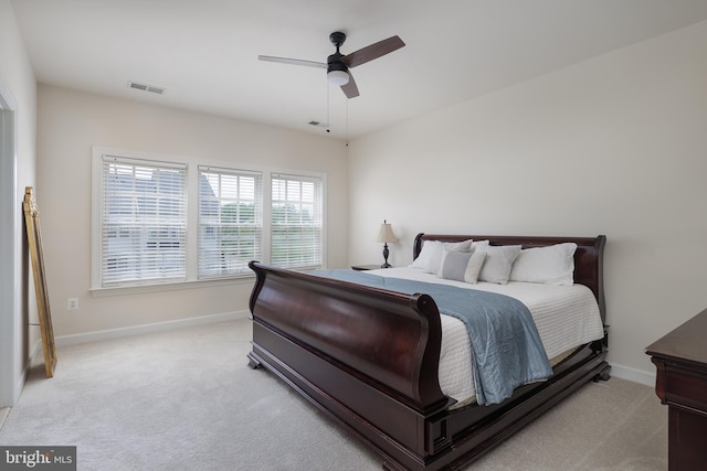 bedroom featuring light colored carpet, visible vents, baseboards, and a ceiling fan