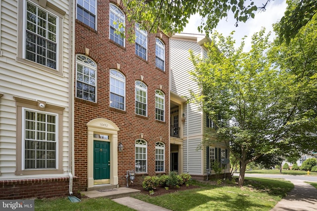 multi unit property with brick siding and a front lawn