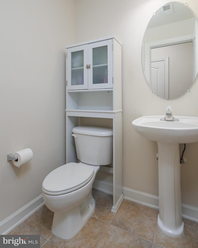 bathroom with toilet, baseboards, and tile patterned floors