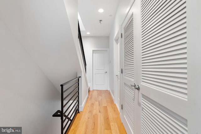 corridor featuring light wood finished floors, an upstairs landing, and recessed lighting