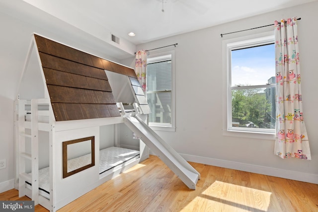 unfurnished bedroom featuring baseboards, multiple windows, and wood finished floors