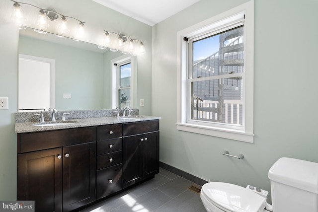 bathroom featuring toilet, a healthy amount of sunlight, and a sink