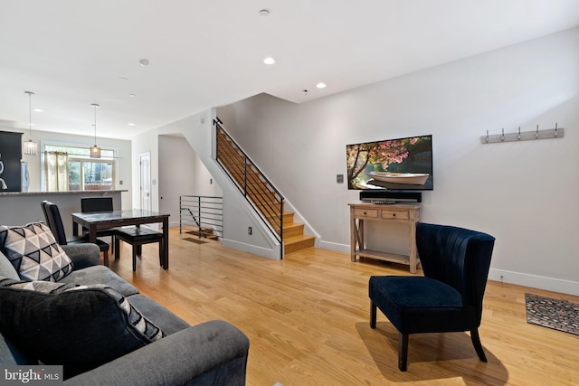 living room featuring stairs, baseboards, light wood-style flooring, and recessed lighting