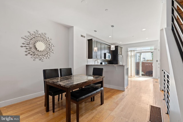 dining room featuring visible vents, light wood-style flooring, baseboards, and recessed lighting