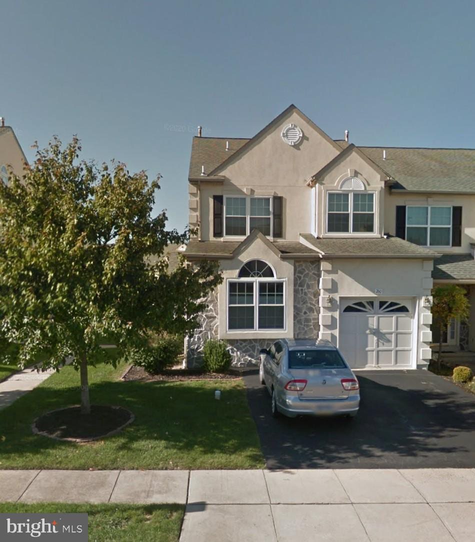 view of front of property featuring aphalt driveway, stone siding, a garage, stucco siding, and a front yard