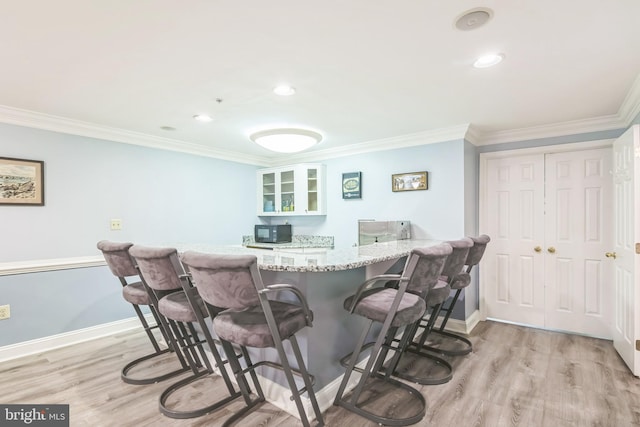760 Whitetail Cir, King Of Prussia, PA 19406 - kitchen featuring a breakfast bar, light wood-type flooring, crown molding, glass insert cabinets, and light stone countertops