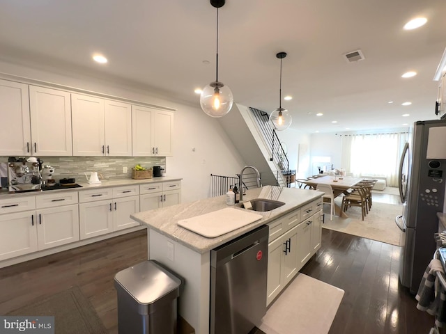 kitchen featuring appliances with stainless steel finishes, a sink, white cabinetry, tasteful backsplash, and dark wood-type flooring