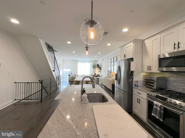 kitchen featuring stainless steel appliances, a sink, open floor plan, recessed lighting, and white cabinets