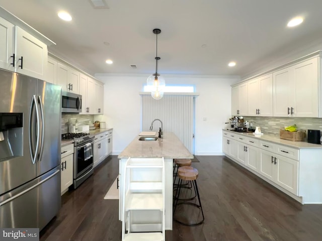 kitchen with stainless steel appliances, a sink, tasteful backsplash, white cabinetry, and ornamental molding