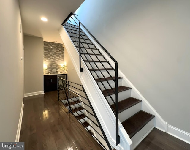 stairway with wood finished floors, baseboards, and recessed lighting