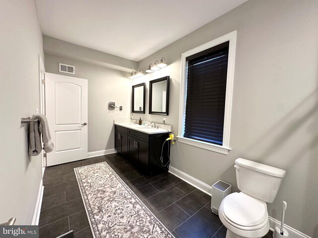 bathroom with baseboards, toilet, double vanity, and tile patterned floors