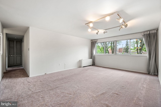 empty room featuring carpet flooring, track lighting, and a chandelier