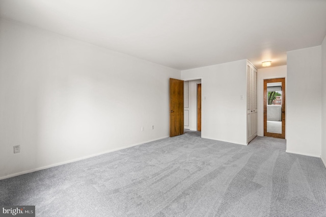 spare room featuring light colored carpet and baseboards