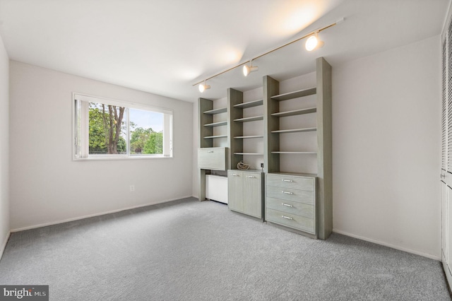unfurnished bedroom featuring light colored carpet, baseboards, and rail lighting