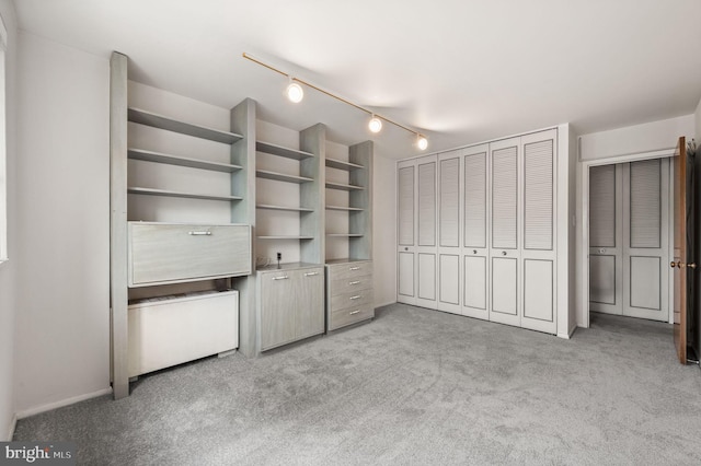 unfurnished bedroom featuring carpet, rail lighting, and a closet