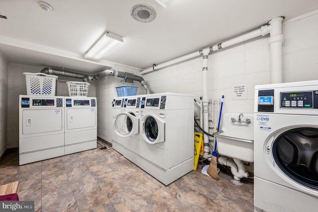 communal laundry room featuring washer and dryer and concrete block wall