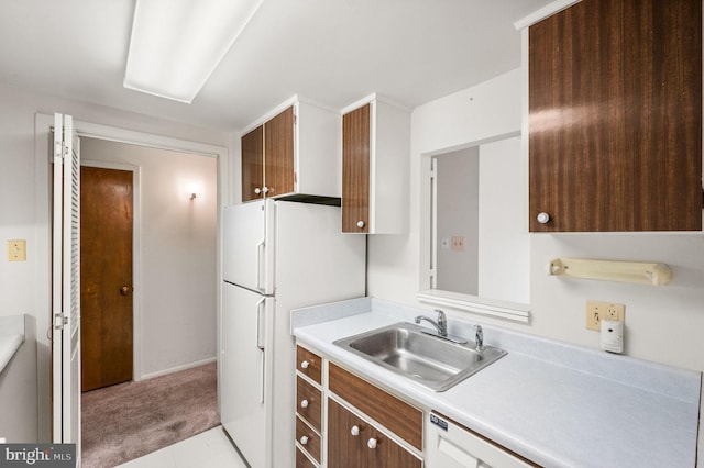 kitchen featuring a sink, light countertops, freestanding refrigerator, and carpet floors