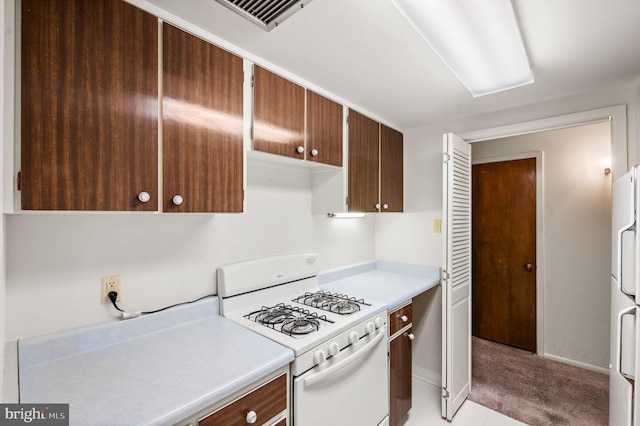 kitchen with white appliances, light countertops, baseboards, and light carpet