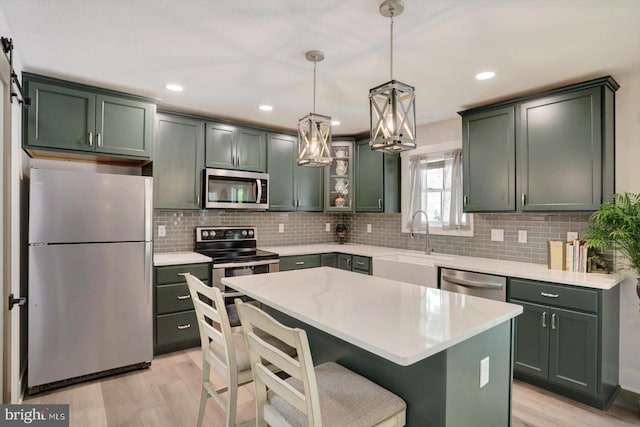 172 Charles St, Hanover, PA 17331 - kitchen with appliances with stainless steel finishes, green cabinetry, a sink, light wood-style flooring, and backsplash