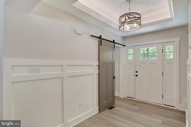 172 Charles St, Hanover, PA 17331 - entryway with a barn door, a raised ceiling, light wood finished floors, a chandelier, and crown molding