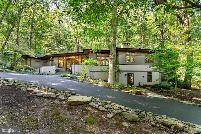 7004 Upper York Rd, New Hope, PA 18938 - mid-century home featuring a view of trees, stucco siding, and a chimney