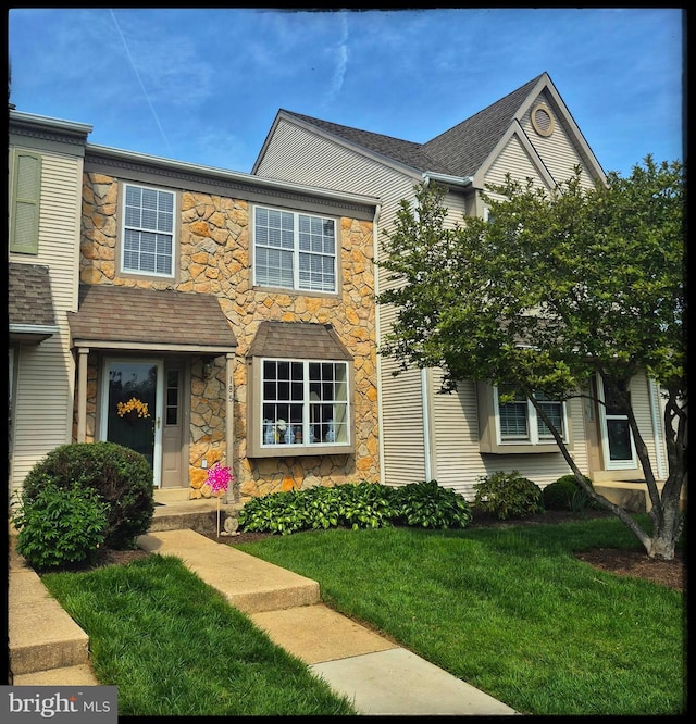 view of property featuring a front lawn and stone siding