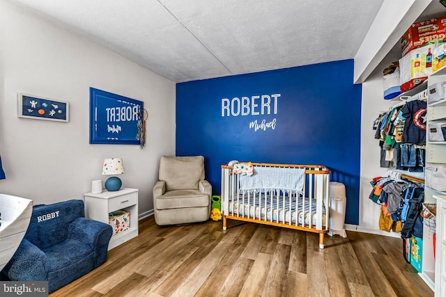 13 Kings Ct Unit 13, Hatboro, PA 19040 - bedroom with wood finished floors, a crib, baseboards, and a textured ceiling