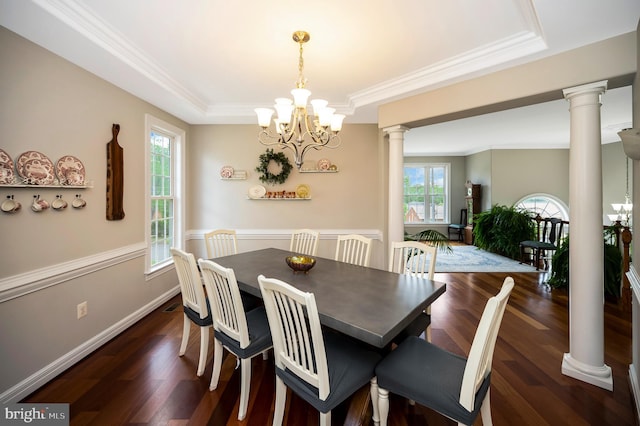 dining room featuring decorative columns, a tray ceiling, ornamental molding, a chandelier, and wood finished floors