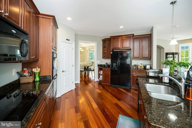 kitchen with black appliances, a sink, dark wood-style floors, hanging light fixtures, and arched walkways