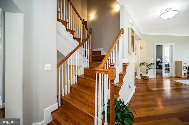 stairway featuring wood finished floors, ornamental molding, and baseboards