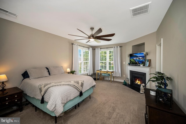bedroom featuring a fireplace with flush hearth, carpet, and ceiling fan