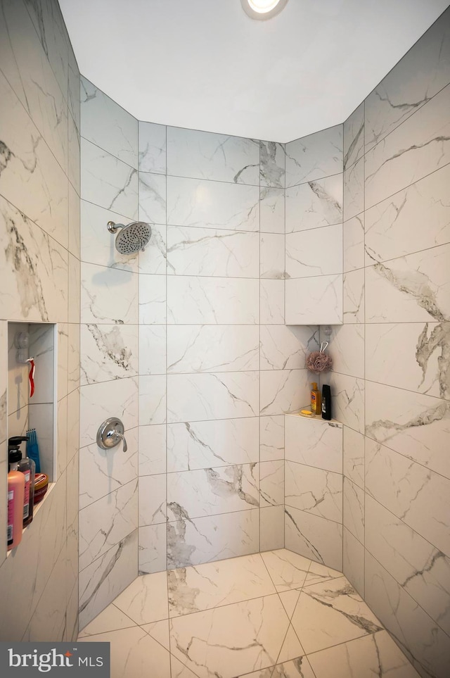 bathroom with a tile shower and marble finish floors